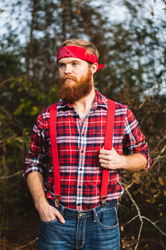 a man wearing a red and blue plaid shirt, red overalls, and a red bandana