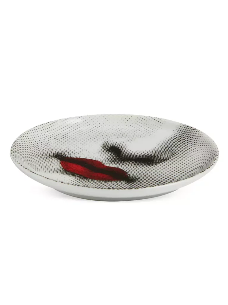A home bar coaster with a woman's nose and bright red painted lips sits on a white background.