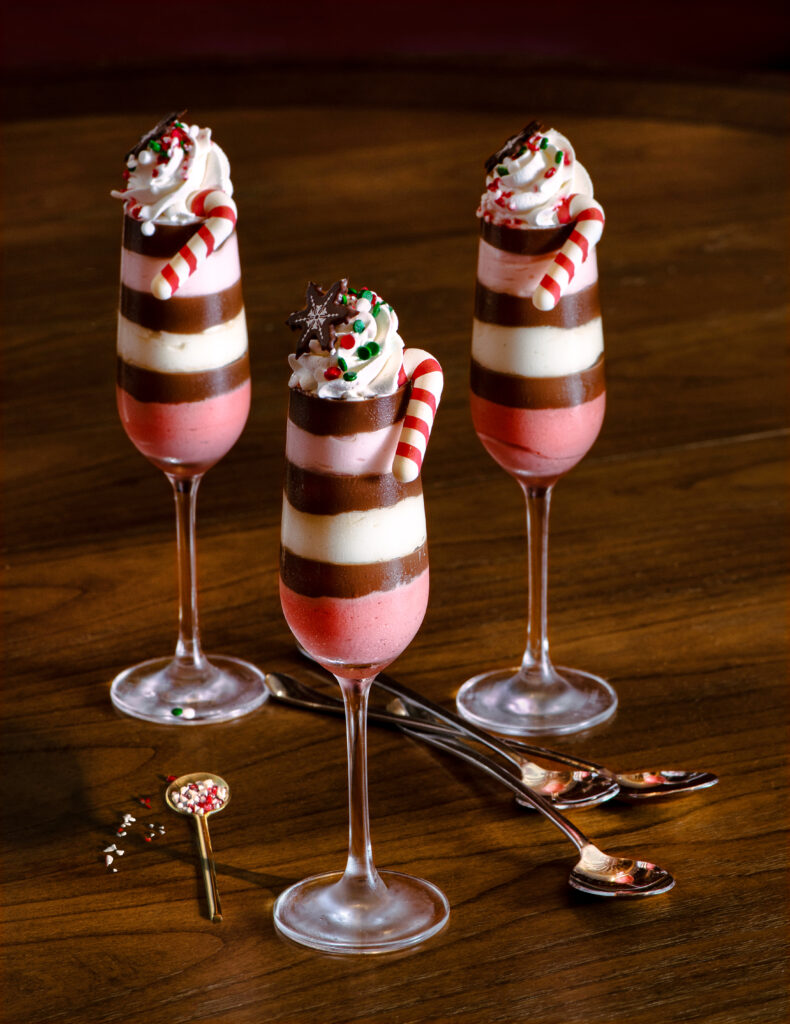 Three champagne flutes filled with peppermint desserts, pink, white, and brown stripes in color.