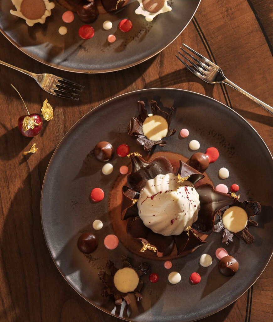 An aerial view of a peppermint dessert on a grey plate drizzled in chocolate and decorated with red and white candy