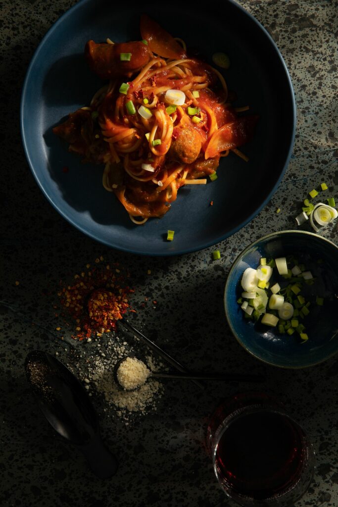 A black bowl of pasta filled with Sausage Sauce made by Victoria Sande.