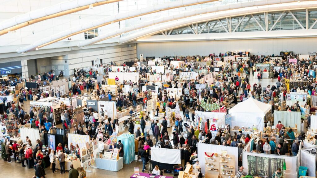 An aerial view of a large crowd of people walking through different vendor booths.