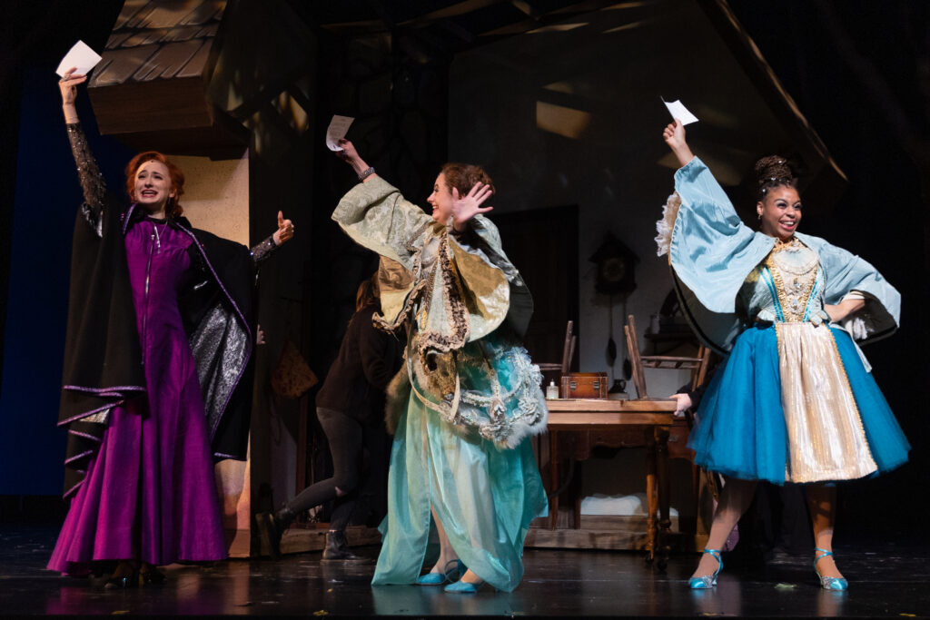 Three actresses stand on stage in Victorian clothing with something in hand at the Pittsburgh Playhouse.