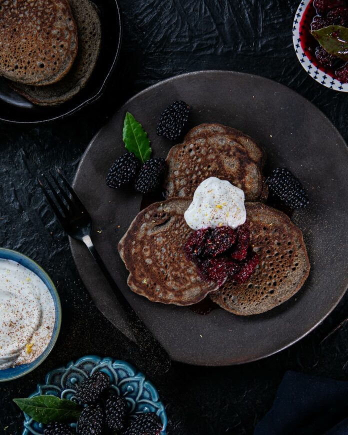 Delectable griddle cakes made with buckwheat flour, topped with a flavorful blackberry sauce infused with bay leaf and black peppercorns.
