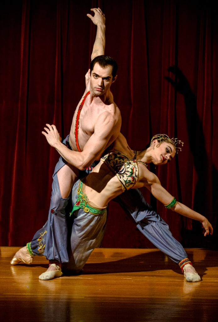 Two dancers intertwine with each other on stage, one male and one female.