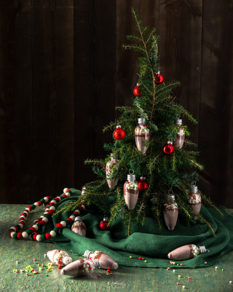 A small Christmas tree decorated with Homemade Hot Cocoa Mix Ornaments.