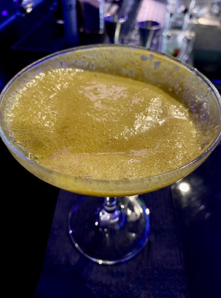 An above view of an orange cocktail with a yellow coconut curry foam at Space Bar in Market Square.