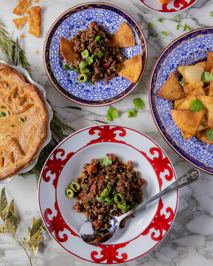 Four colorful plates filled with mounds of picadillo: meat, seasonings, and pies.