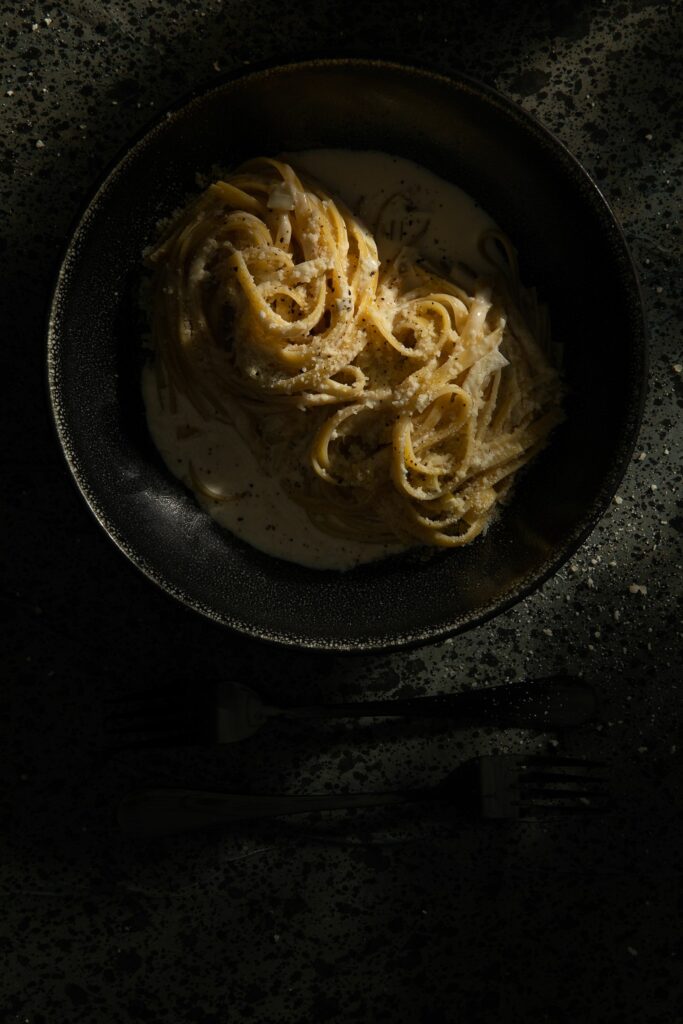 A black dish filled with Fettucine Aldredo made from the Homamde Italian Recipes of Victoria Sande.