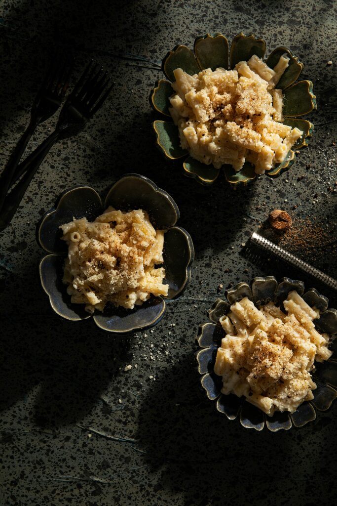 Three mini black bowls filled with pasta coated in Victoria Sande's Homemade Italian Recipe White Sauce.