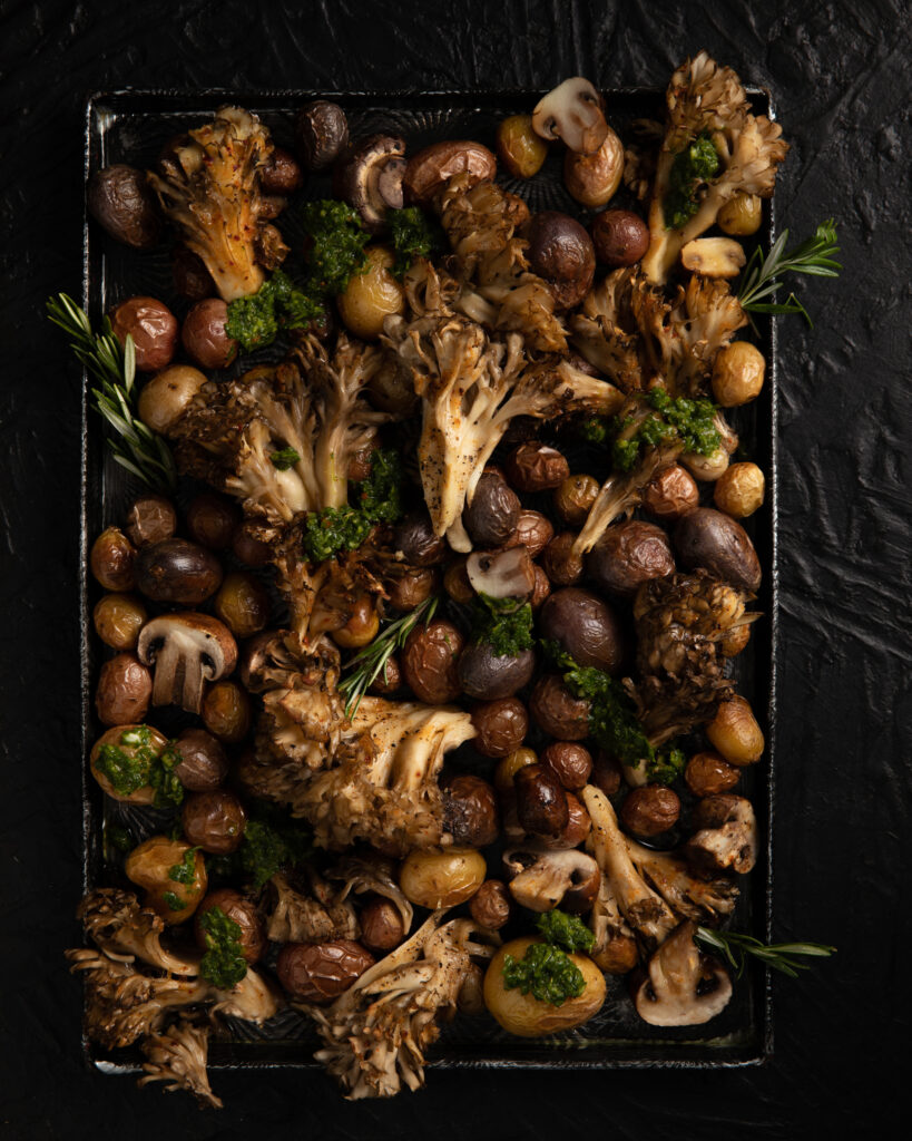 Roasted Wild Mushrooms and Potatoes with Chimichurri served in a black tray with a black background