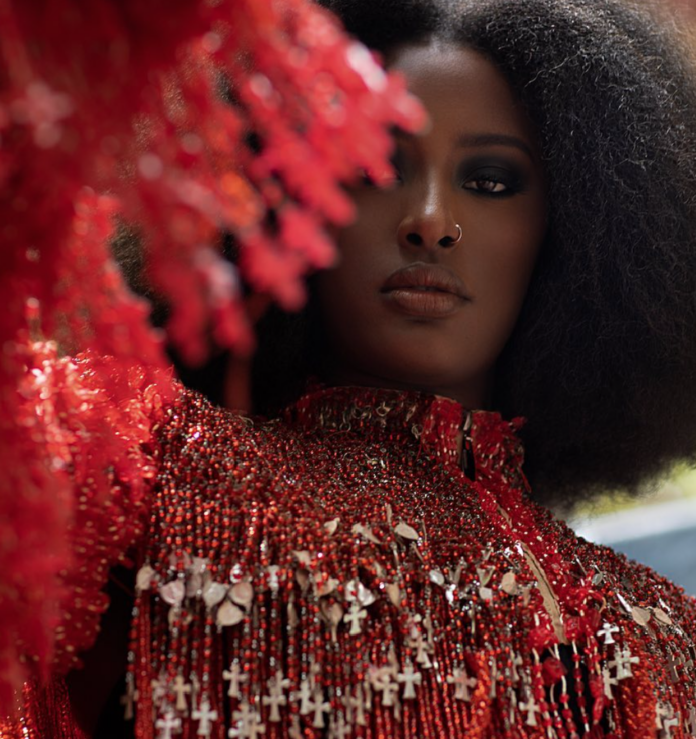 A woman with dark hair holds up the fringed arm of a red jacket.