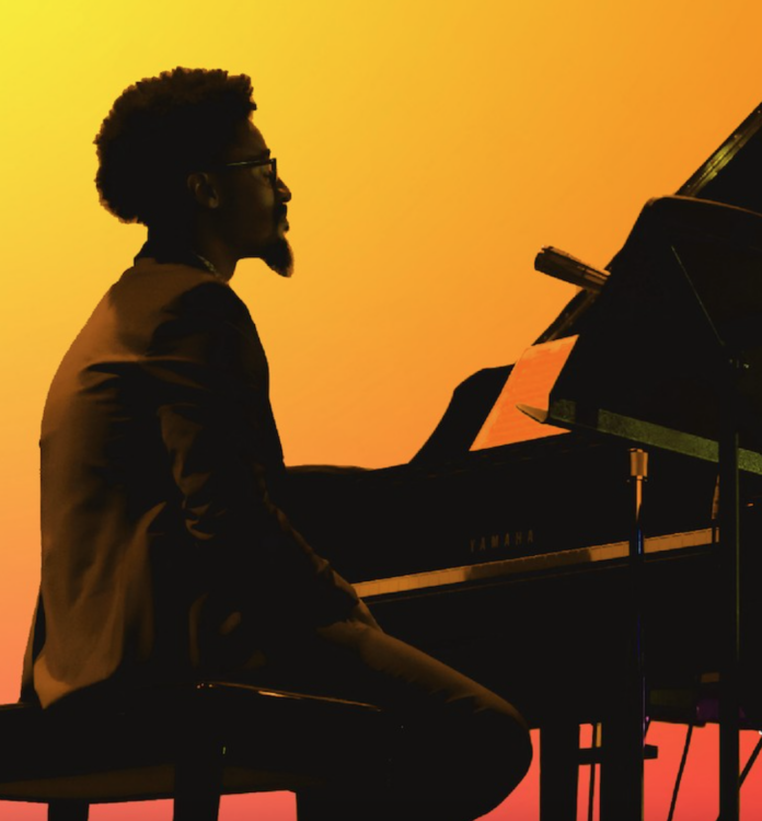 A silhouette of a man sits at a piano in front of yellow and orange lights at the Kelly Strayhorn Theater's Suite Life