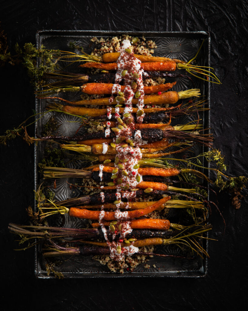 Sheet Pan roasted carrots served on a black tray with Tahini sauce