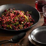 Farro served with Beets, Greens & Ginger Dressing in a skillet with a spoon on the side