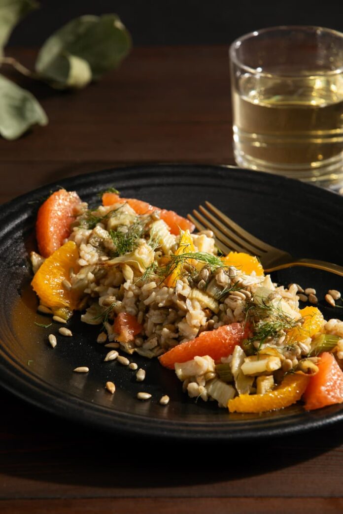 Brown Rice and Lentil Salad with Citrus & Roasted Fennel served in a black plate with a steel fork