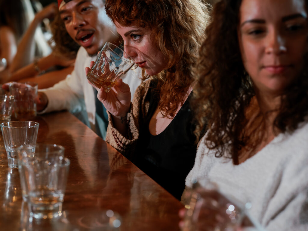 Three people drink at a local Pittsburgh distillery with empty glasses in front of them. 