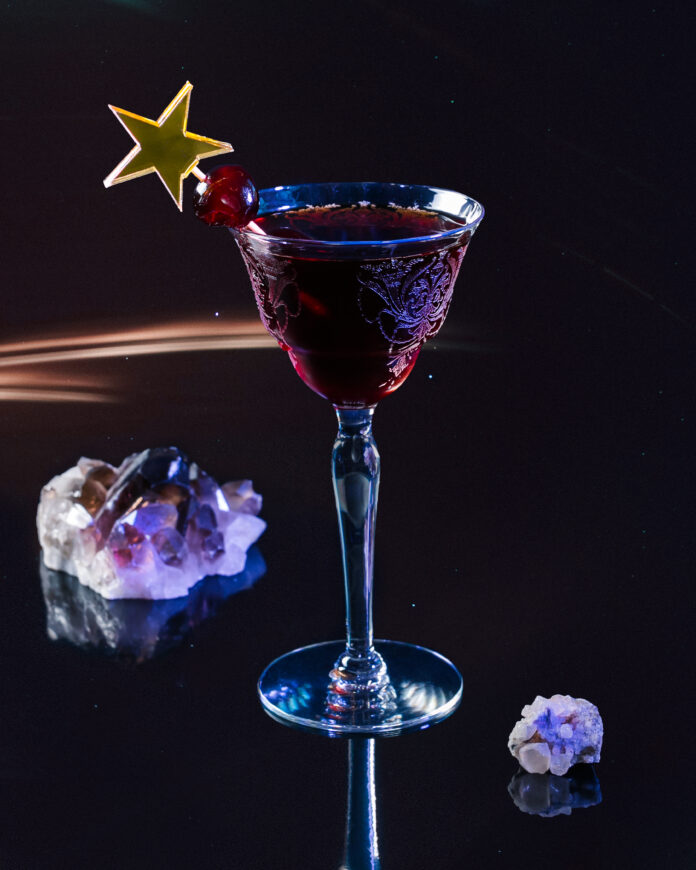 Black Manhattan, A Cocktail for Capricorn A Black Manhattan cocktail for Capricorn in a fancy glass with a star topper cocktail stick and crystals around the glass.
