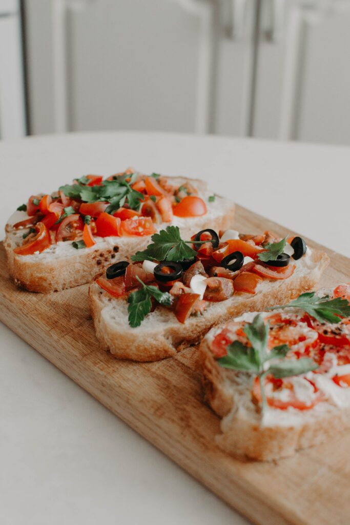 A New Year's Eve Hors D'oeuvres of three slices of tomato bruschetta on top of white italian bread with basil and olives.