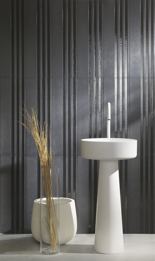 A black and grey textured tile wall sits behind a white table and white plant holder.