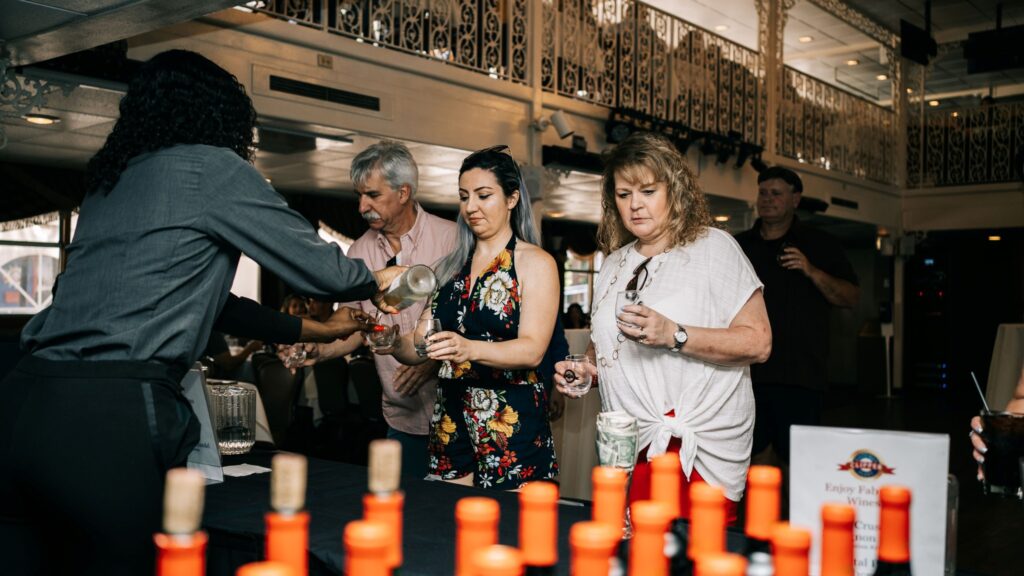 Three people wait for another person to pour them a glass of wine inside the Gateway Clipper in Pittsburgh