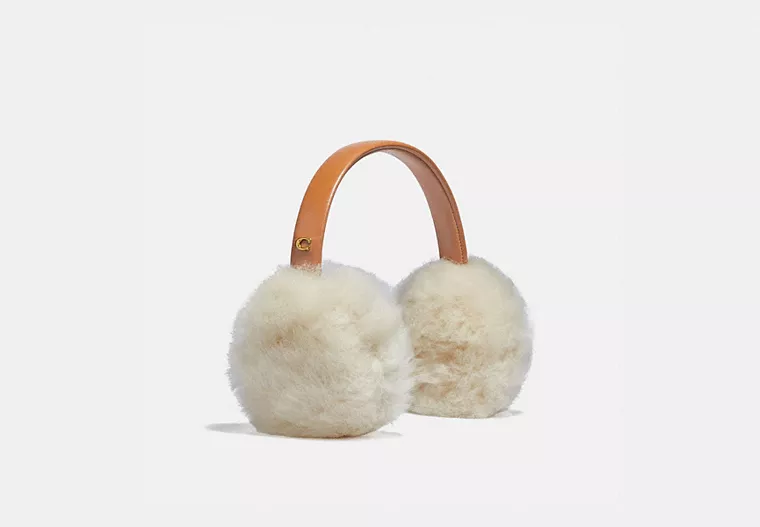 A set of earmuffs with a brown band and cream colored big puffs sits on a white background.