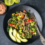 California Quinoa Salad served in a dark black plate with a steel fork