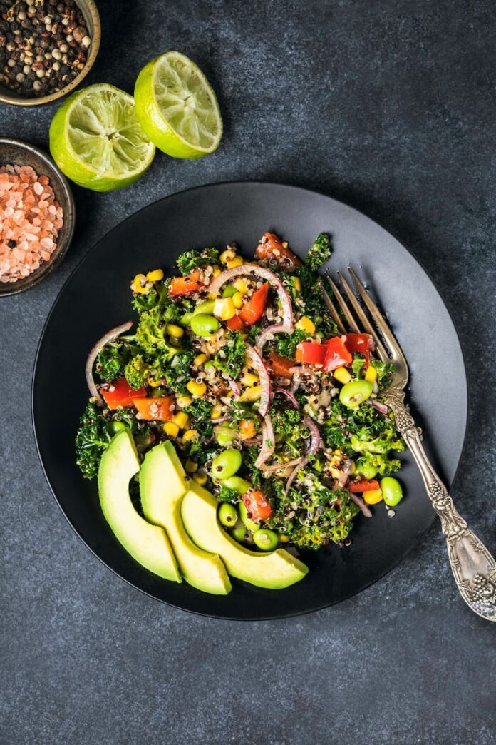 California Quinoa Salad served in a dark black plate with a steel fork