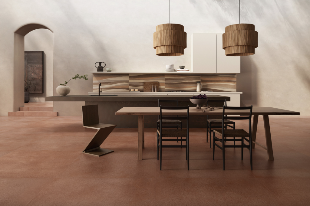 A dining room is themed with desert rock red tiles with a minimalist brown dining table and chairs in the center of the room.