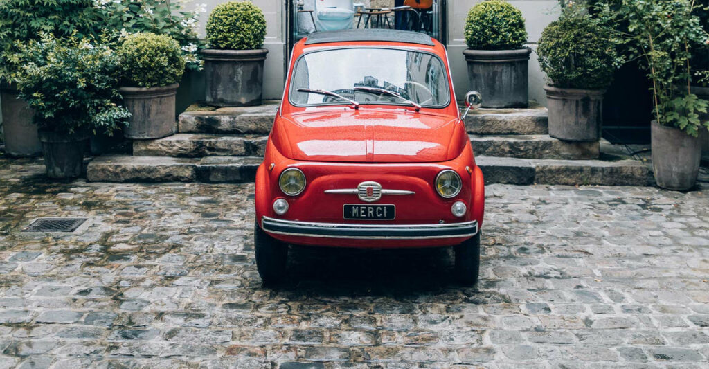 A red fiat with the license plate "Merci" sits on stone in front of the Merci design shop in Paris.