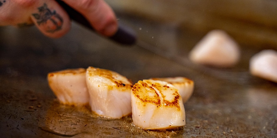 A person's hand temperature tests scallops that are being seared in a pan at Ritual House in Pittsburgh.