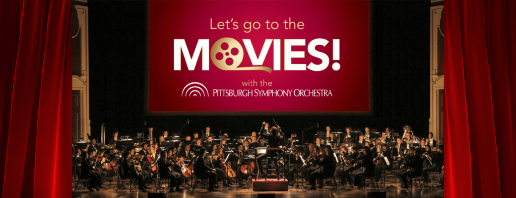 The Pittsburgh Symphony Orchestra plays on the stage at the Heinz Hall in front of a projector that reads "Let's go to the movies"