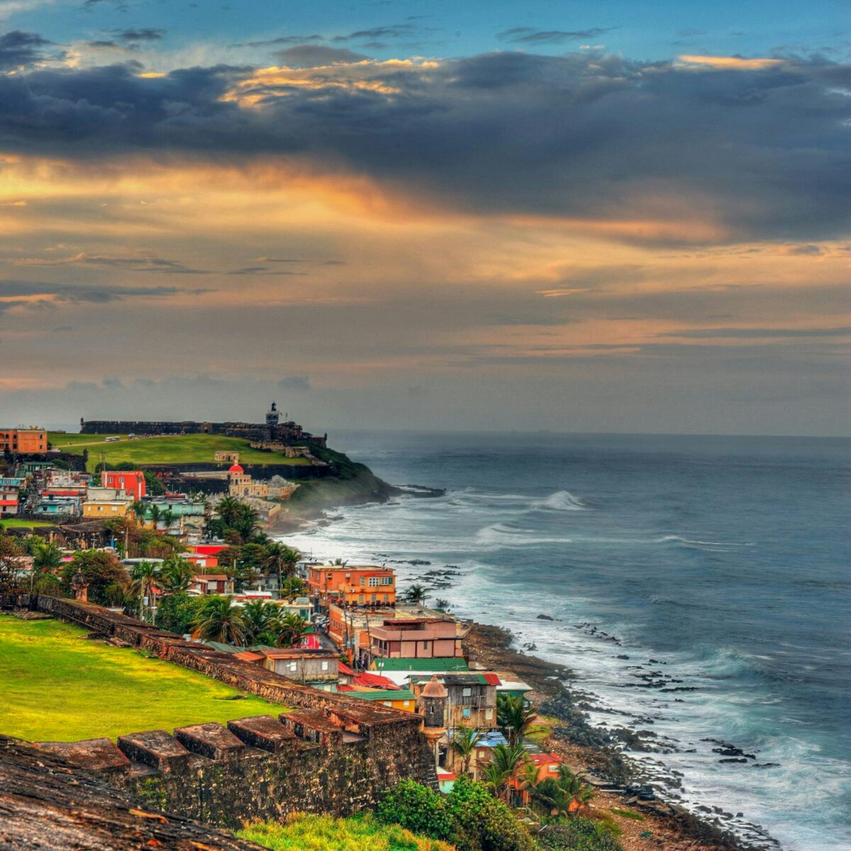 A photo of the coast of Puerto Rico, a unique spring break destination, lined with building along the shore and a blue ocean crashing up against it.