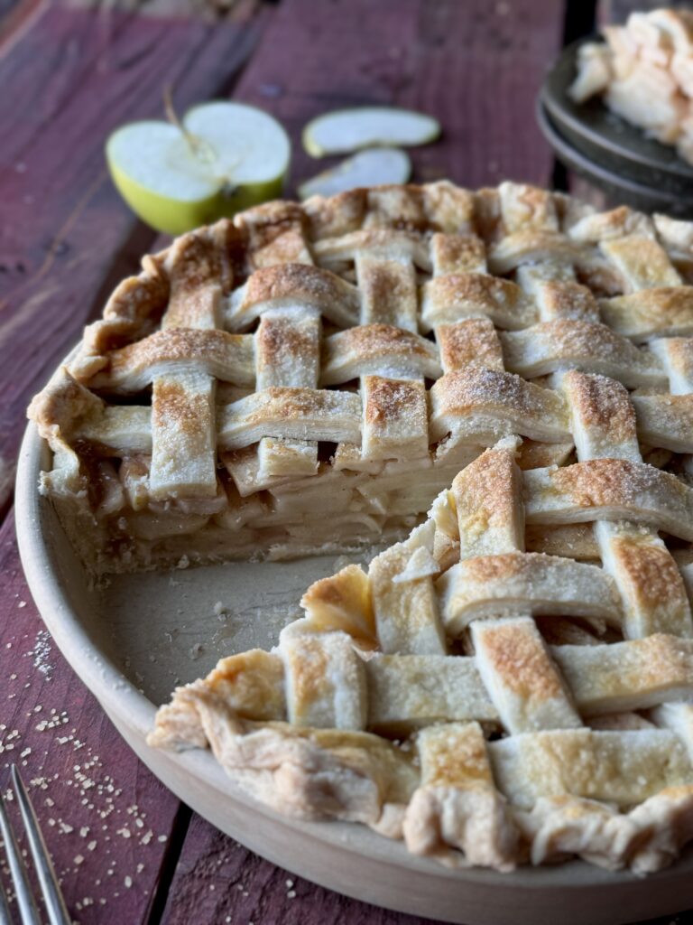 A traditional apple pie with a lattice top crust and a slice removed.