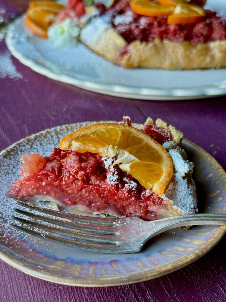 A slice of raspberry orange galette on a small plate with a fork.