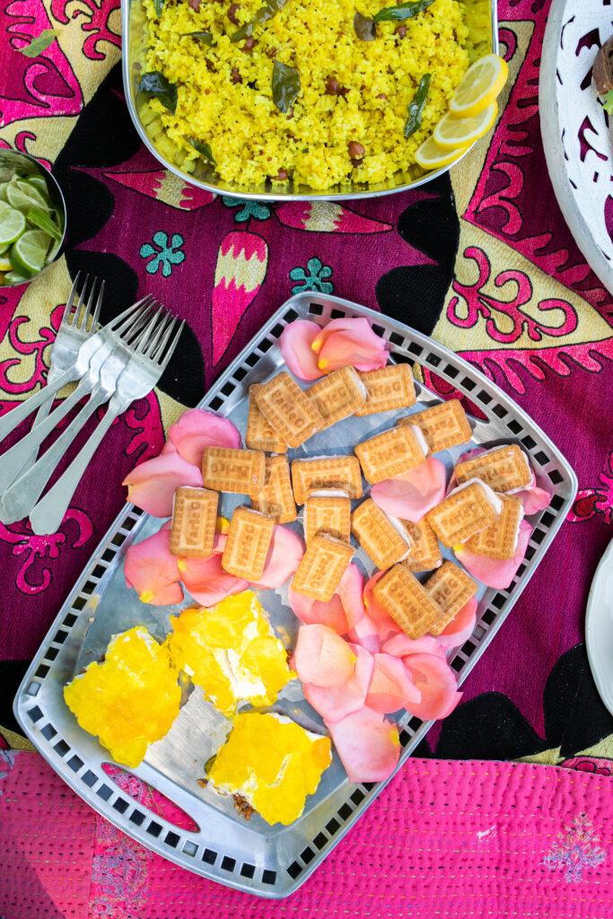Rose milk sandwich cookies served in a steel plate, which is placed on a colorful cloth
