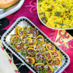 Aloo Tikki served on a rectangular tray, which is placed on a reddish cloth