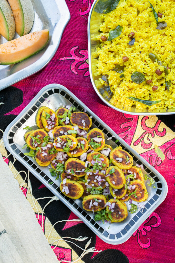 Aloo Tikki served on a rectangular tray, which is placed on a reddish cloth