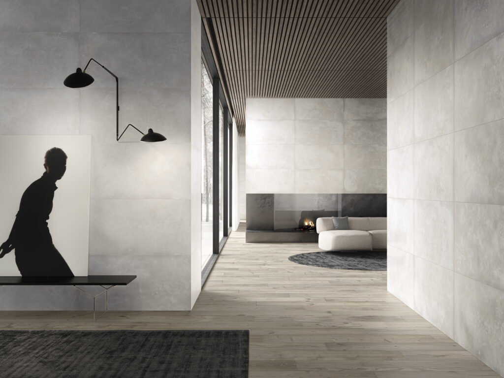 A room with stone washed walls, a shadow of a person on the left, and upscaled couches and tables.