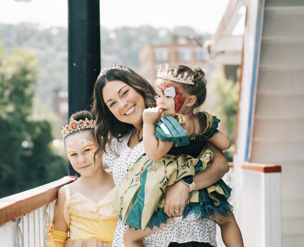 A woman holds one child in a princess dress while the other in a princess dress stands next to her on the Gateway Clipper for a family-friendly Valentine's Day