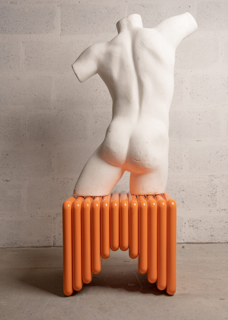 An orange unique stool by Senimo featured at the Maison&Objet show with a white sculpture of a man sitting on top.
