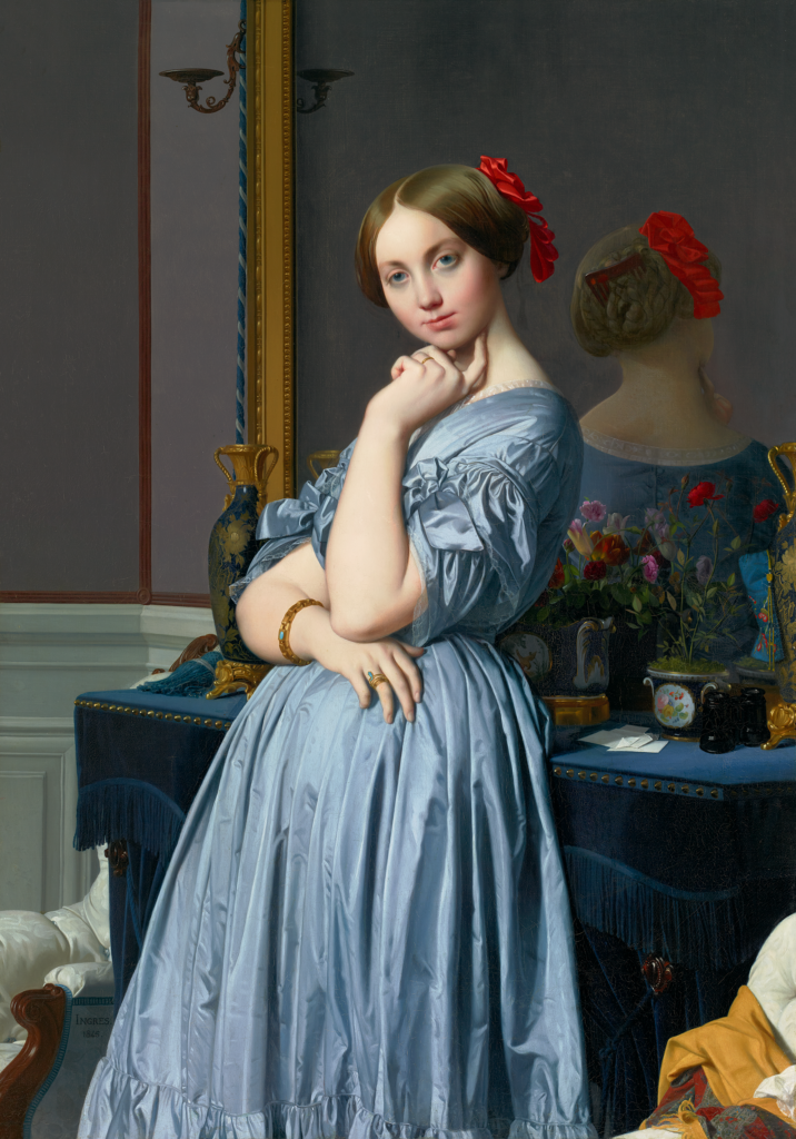 A girl in a blue dress poses in a painting with a red bow in her hair and her reflection in the mirror behind her now at The Frick Pittsburgh.
