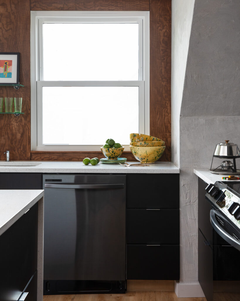 A picture of a kitchen counter with a dish washer built into the side and a side window above it.