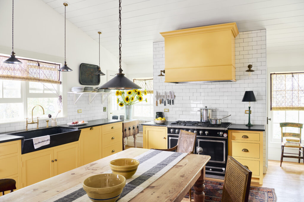 A kitchen painted with white and yellow paint with black accents on the stove, sink, and lights.