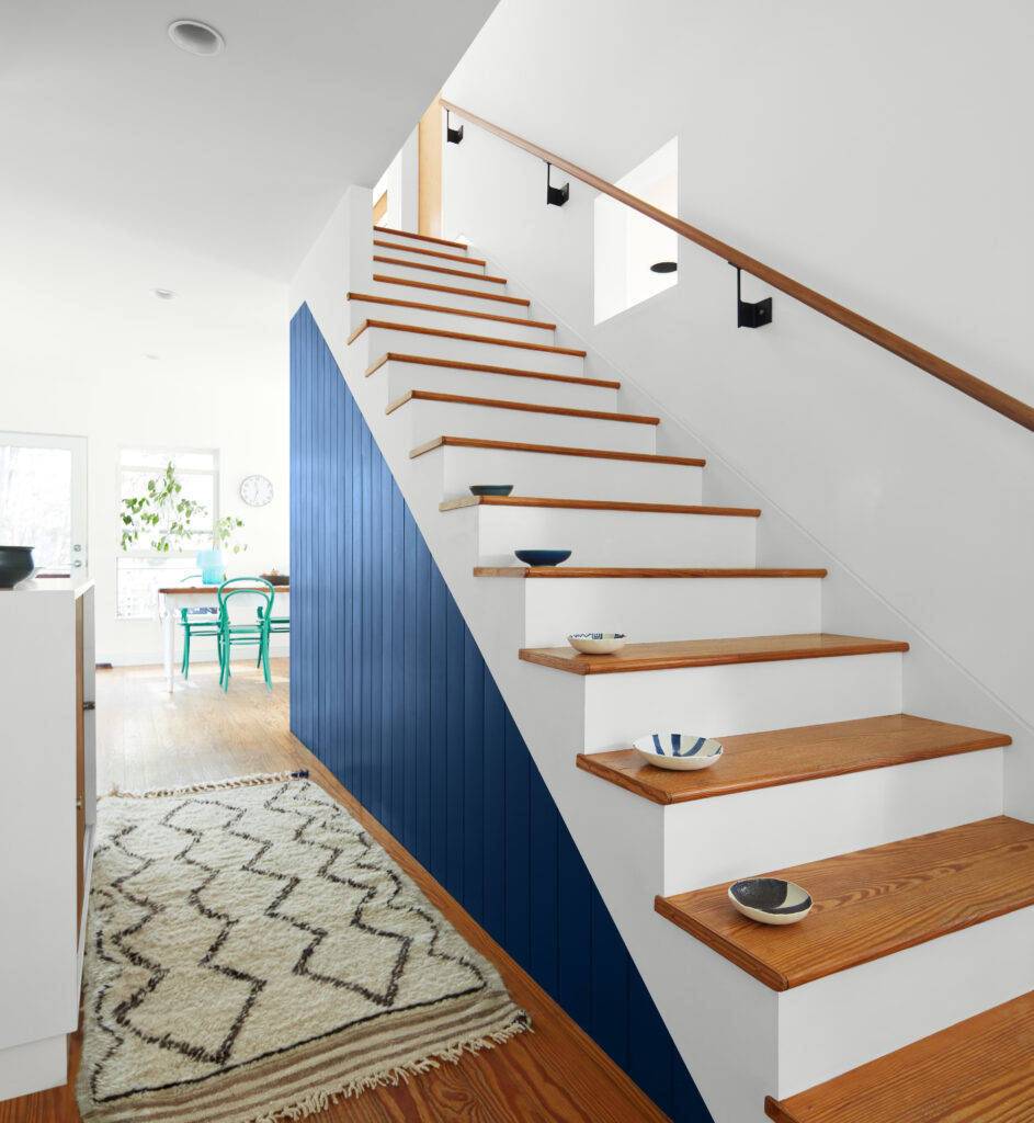 A set of wooden stairs painted white with the side painted a dark blue spring color.