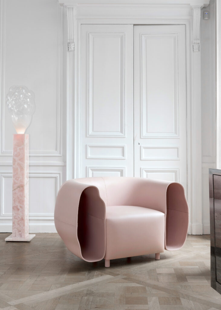 In a white room sits a pink elephant armchair and a pink smoke lamp with a glass globe.