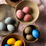 Bowls of dyed Easter eggs in yellow, blue, pink, and grey.