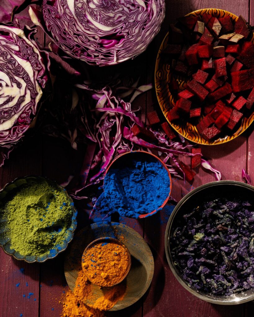 Powders and vegetables in vibrant colors on a purple table.