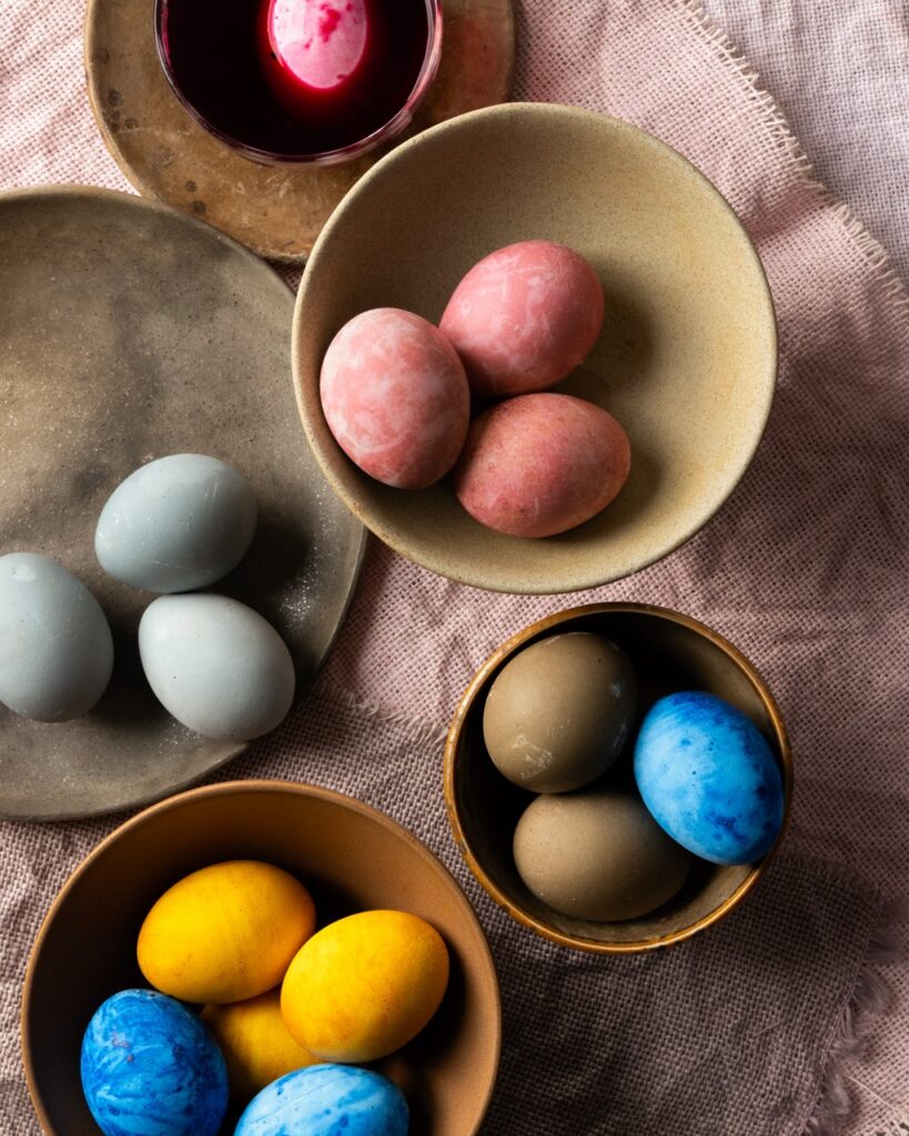 Bowls of dyed Easter eggs in yellow, blue, pink, and grey.
