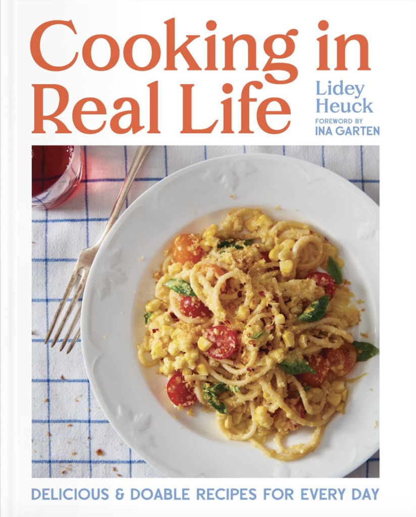 A cover of the cookbook "Cooking in Real Life" by Lidey Heuck featuring a picture of a pasta recipe in a white dish.